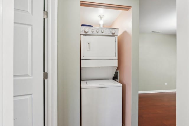 washroom with stacked washer / drying machine and hardwood / wood-style flooring