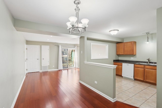 kitchen featuring sink, light hardwood / wood-style flooring, dishwasher, an inviting chandelier, and hanging light fixtures