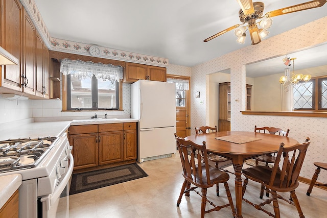 kitchen featuring white appliances, decorative light fixtures, tasteful backsplash, sink, and ceiling fan