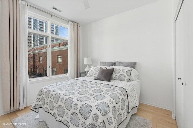 bedroom with light wood-type flooring, ceiling fan, and a closet