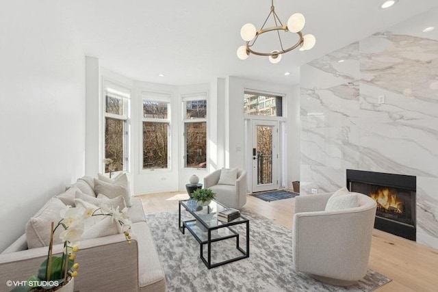 living room with tile walls, a chandelier, a high end fireplace, and light hardwood / wood-style flooring