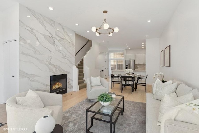 living room featuring wood-type flooring, a premium fireplace, tile walls, and a notable chandelier