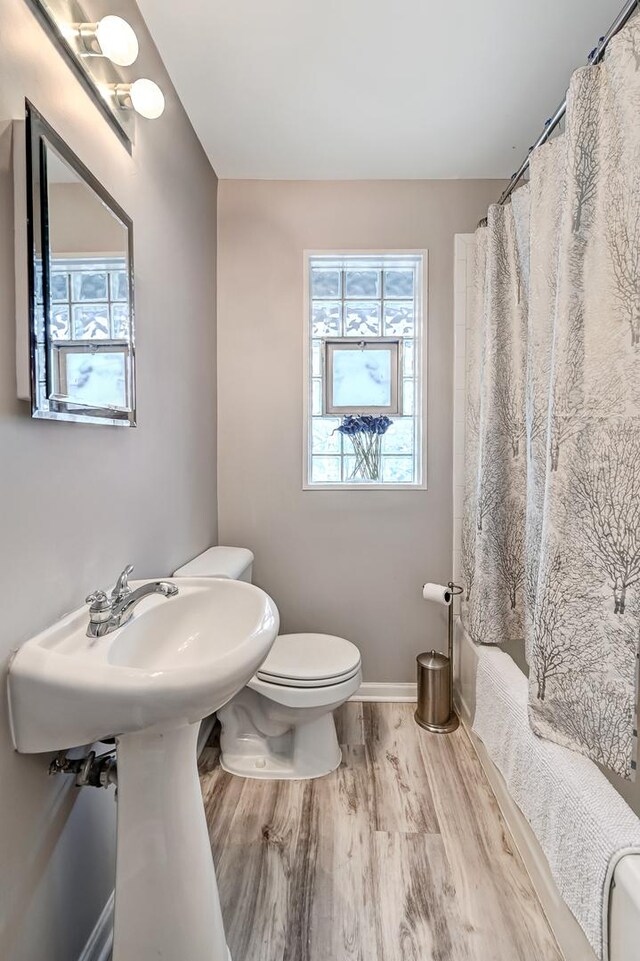 bathroom featuring hardwood / wood-style flooring, walk in shower, and toilet