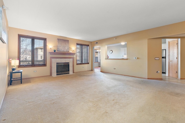 unfurnished living room with a tiled fireplace and light colored carpet