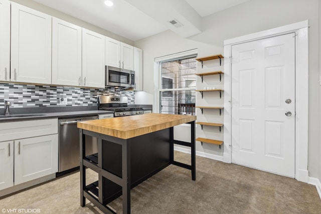 kitchen featuring butcher block countertops, sink, appliances with stainless steel finishes, decorative backsplash, and white cabinets