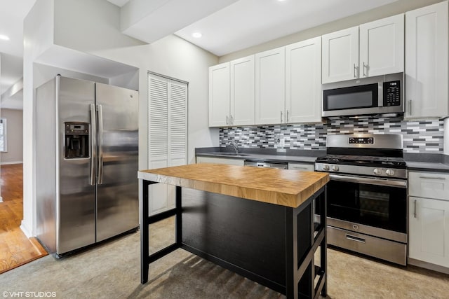 kitchen with a kitchen island, appliances with stainless steel finishes, butcher block counters, sink, and white cabinets