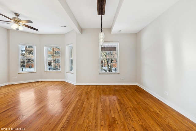 spare room featuring ceiling fan, hardwood / wood-style flooring, and beamed ceiling