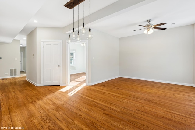 unfurnished dining area featuring beamed ceiling, ceiling fan, and light wood-type flooring