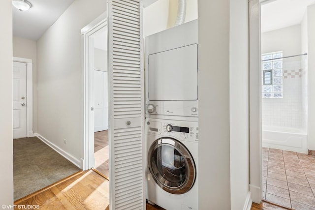 clothes washing area with wood-type flooring and stacked washing maching and dryer