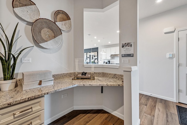 kitchen with white cabinetry, light hardwood / wood-style flooring, and light stone countertops