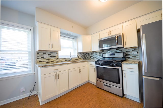 kitchen with sink, white cabinets, appliances with stainless steel finishes, and tasteful backsplash