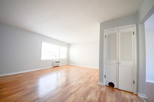 unfurnished bedroom with a closet, light wood-type flooring, and a wall mounted AC