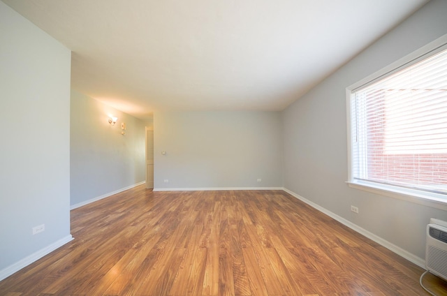 empty room with an AC wall unit, dark wood-type flooring, and plenty of natural light