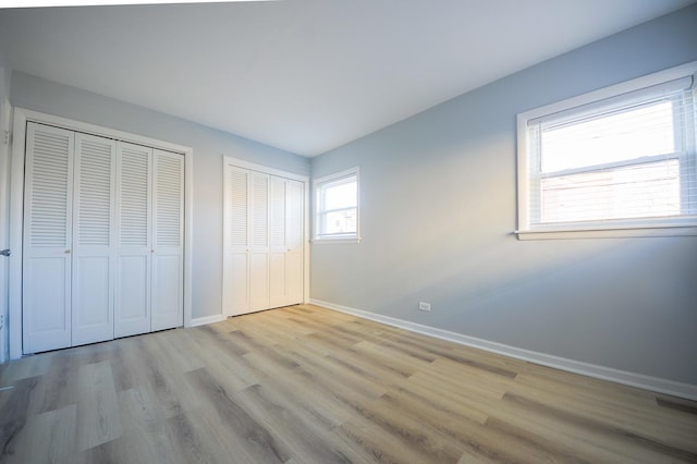 unfurnished bedroom featuring light hardwood / wood-style floors and two closets