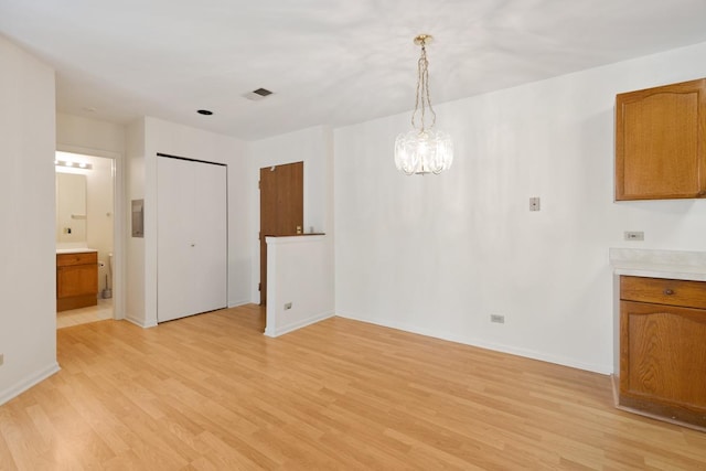 unfurnished dining area with an inviting chandelier and light hardwood / wood-style flooring