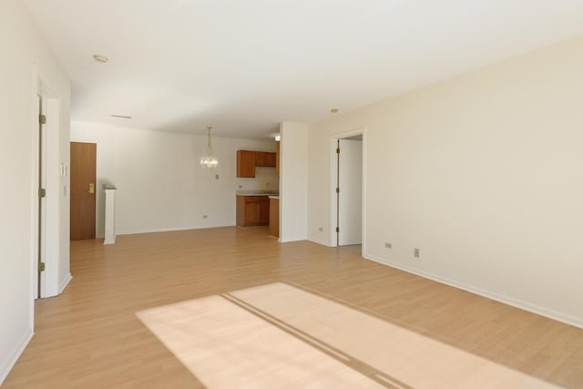 unfurnished room with a chandelier and light hardwood / wood-style floors