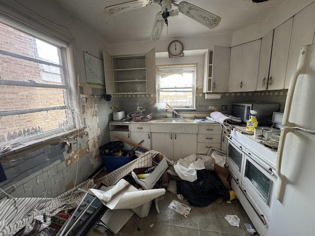 kitchen featuring sink, white cabinetry, white appliances, and a wealth of natural light