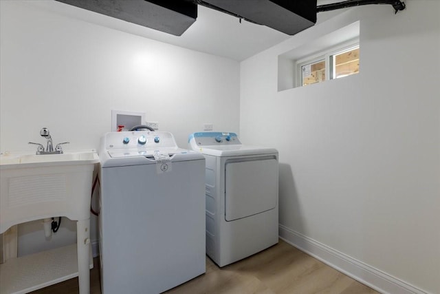 clothes washing area featuring washer and clothes dryer and light hardwood / wood-style floors