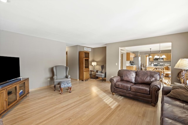 living room featuring a notable chandelier and light wood-type flooring