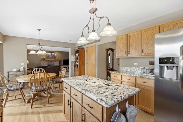 kitchen featuring a kitchen island, hanging light fixtures, stainless steel fridge with ice dispenser, light stone countertops, and light hardwood / wood-style flooring