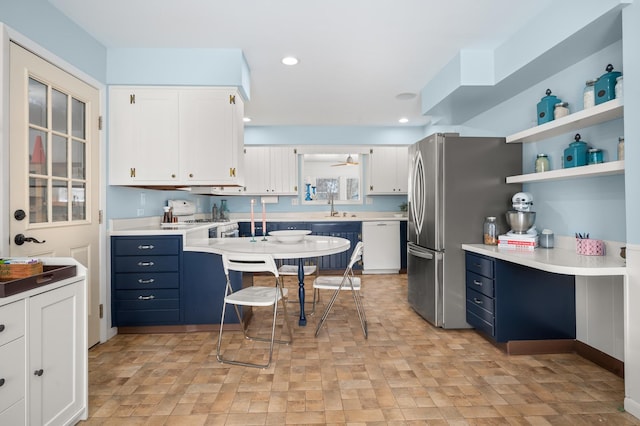 kitchen featuring ceiling fan, sink, blue cabinetry, white cabinetry, and white appliances