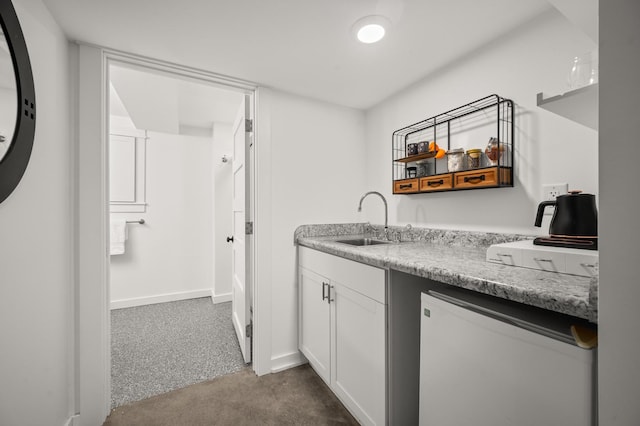 kitchen with sink, white cabinetry, fridge, and dark carpet