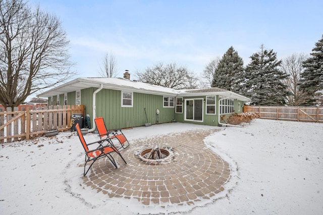 snow covered rear of property with a patio area and an outdoor fire pit