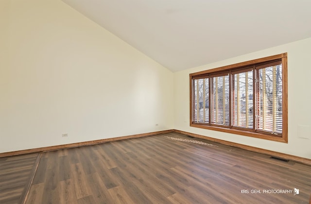 spare room featuring vaulted ceiling and dark wood-type flooring