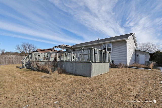 rear view of house with a wooden deck and a lawn