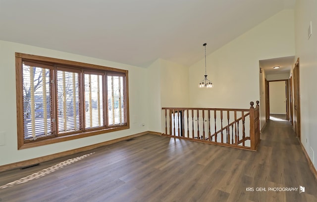 spare room with lofted ceiling, dark hardwood / wood-style floors, and an inviting chandelier