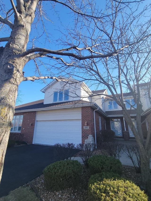 view of front facade with a garage, driveway, and brick siding