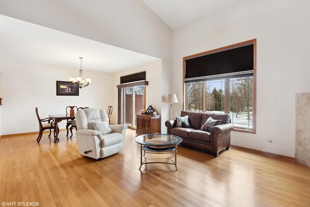 living room featuring a wealth of natural light, a notable chandelier, and light hardwood / wood-style flooring