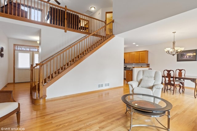 living room with a chandelier, light hardwood / wood-style flooring, and a high ceiling