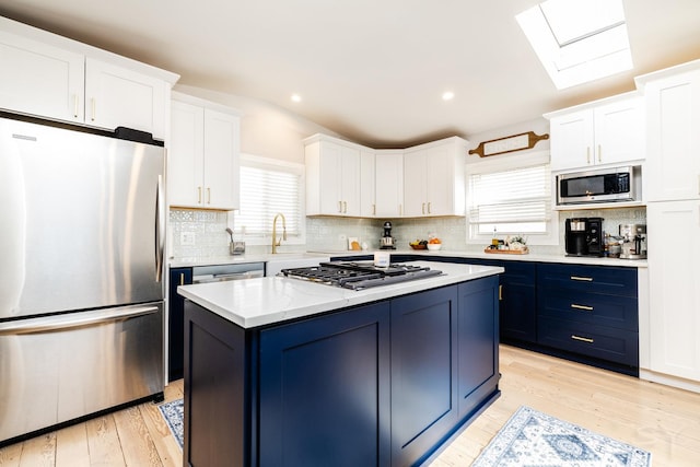 kitchen with a kitchen island, white cabinetry, appliances with stainless steel finishes, and blue cabinets