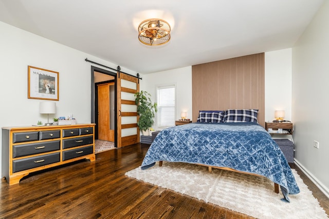 bedroom with a barn door and dark hardwood / wood-style flooring