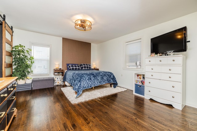 bedroom with dark wood-type flooring and a barn door