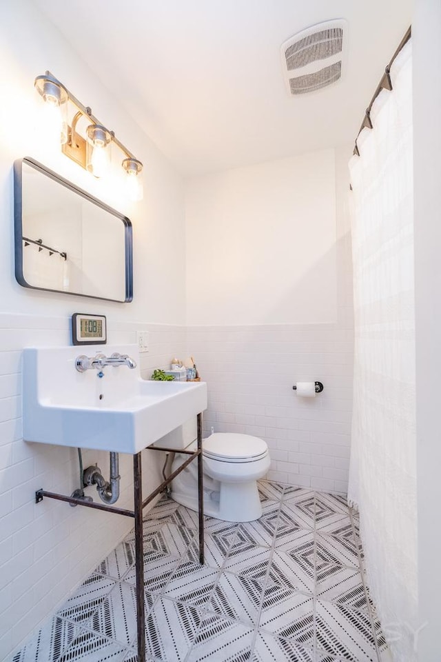 bathroom featuring sink, tile walls, and toilet