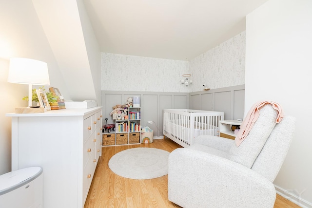 bedroom with a nursery area and light wood-type flooring