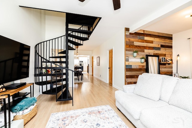 living room featuring ceiling fan, wooden walls, beamed ceiling, and wood-type flooring