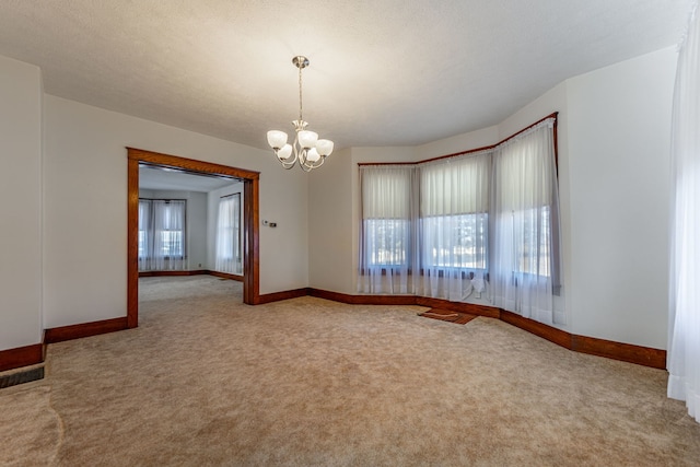 spare room featuring baseboards, carpet floors, plenty of natural light, and an inviting chandelier