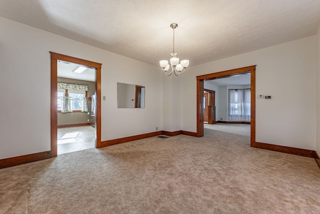 carpeted spare room featuring a chandelier and baseboards