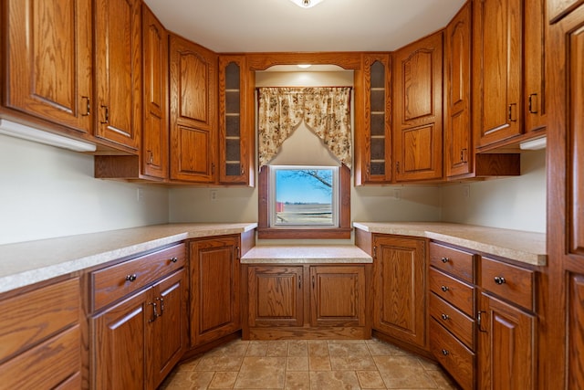 kitchen with glass insert cabinets, brown cabinets, and light countertops