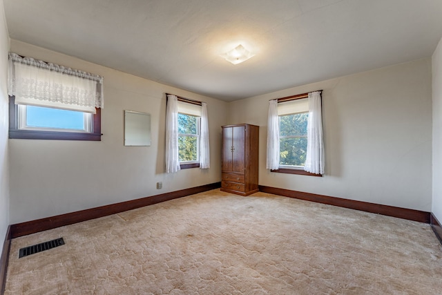 carpeted spare room featuring baseboards and visible vents