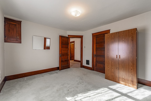 unfurnished bedroom featuring a closet, light carpet, and baseboards