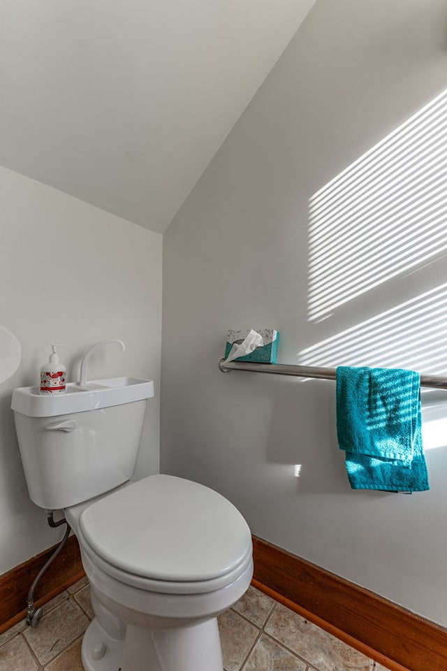 bathroom with lofted ceiling, tile patterned floors, toilet, and baseboards