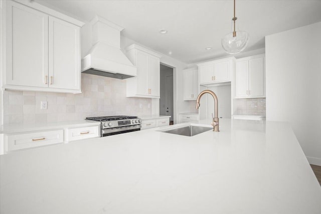 kitchen featuring pendant lighting, sink, stainless steel range with gas stovetop, and white cabinets