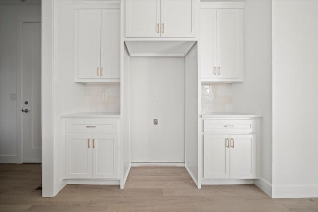 interior space with white cabinets, light hardwood / wood-style floors, and decorative backsplash