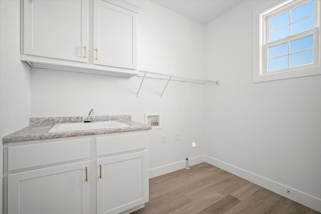 laundry area featuring cabinets, sink, washer hookup, and light hardwood / wood-style floors