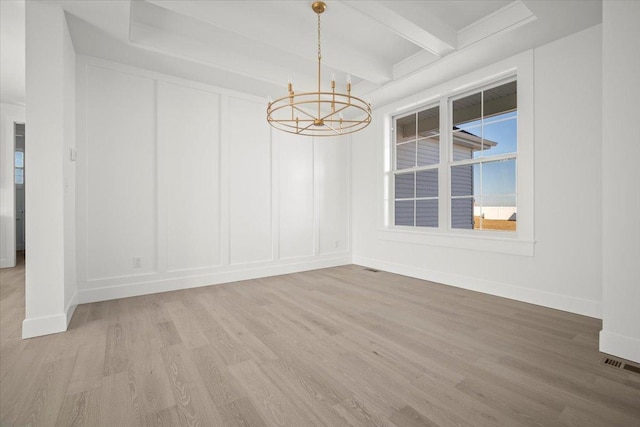 empty room with an inviting chandelier, hardwood / wood-style floors, and beam ceiling