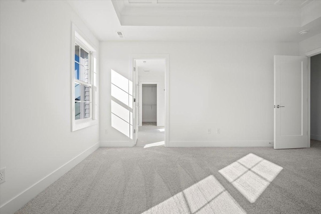 carpeted spare room featuring a raised ceiling